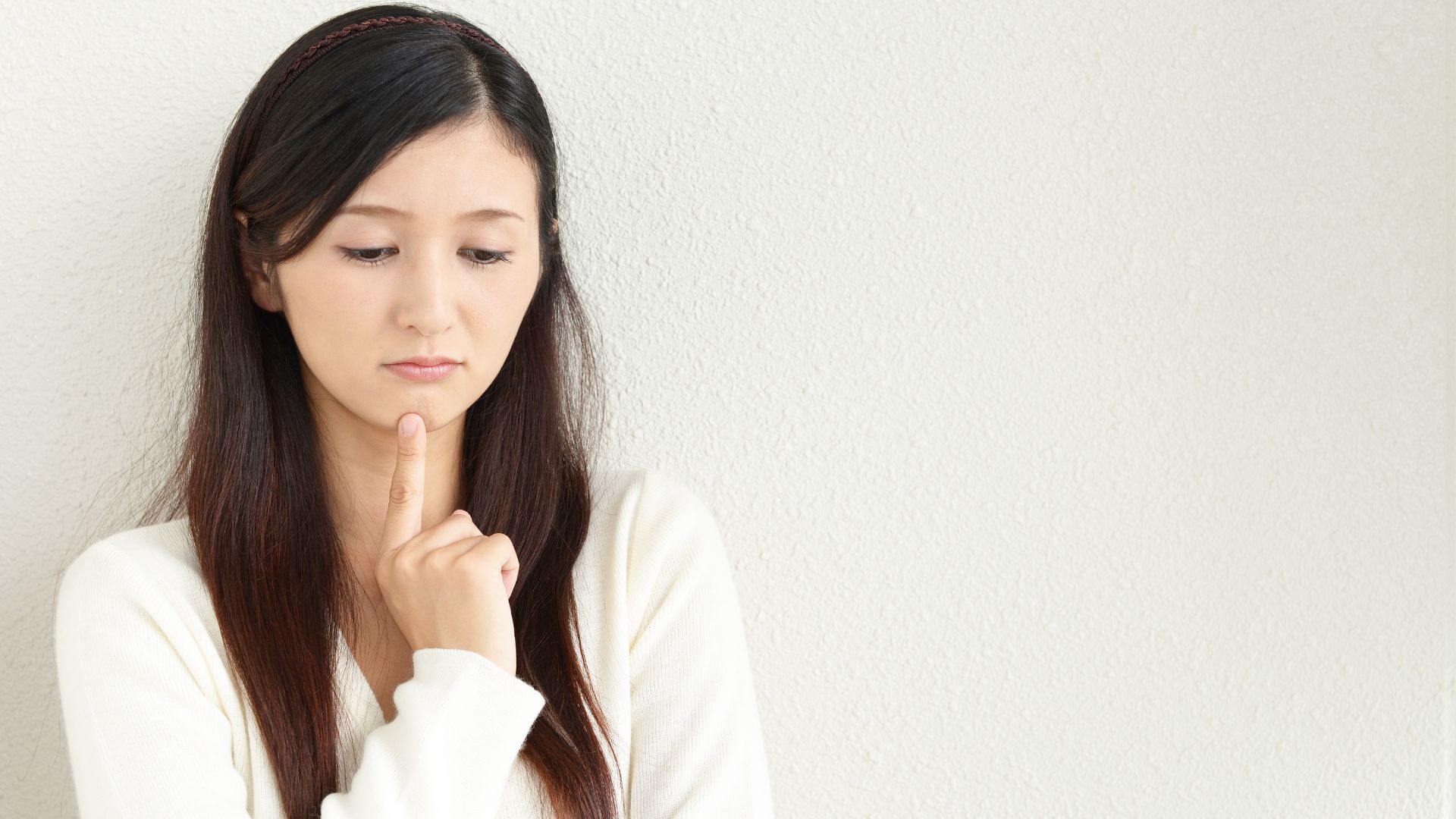 「なんとなく調子が悪い」と感じ、顎に手を当てて考え込む女性。自律神経の乱れのサイン。